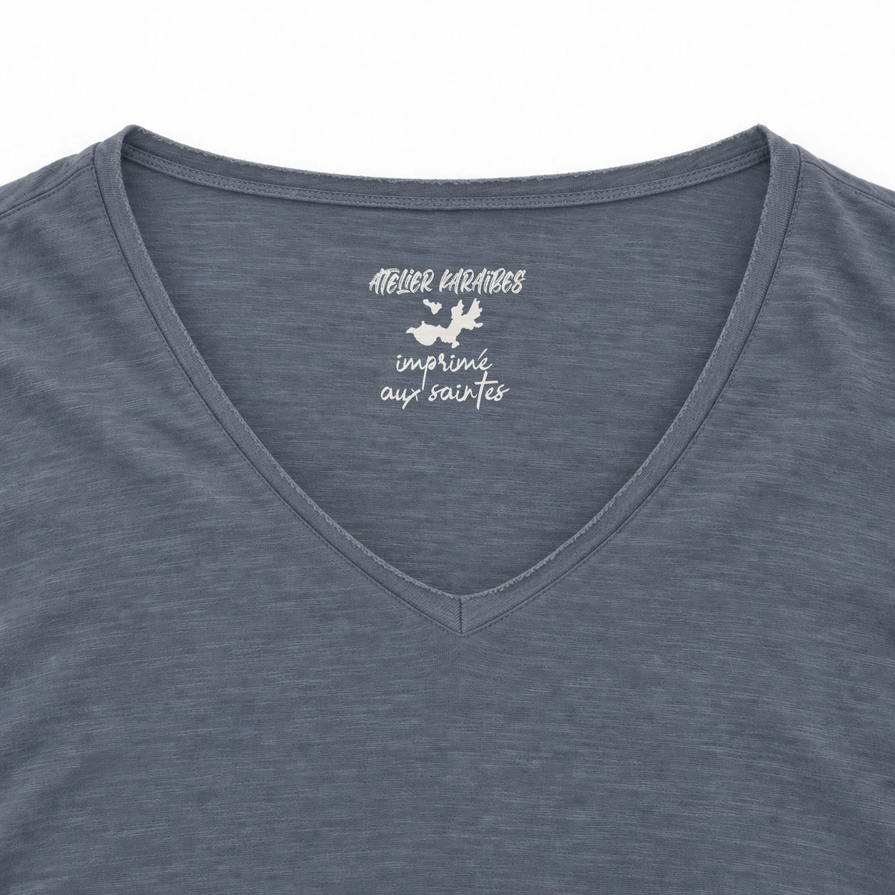 Étiquette intérieure Atelier Karaïbes « imprimé aux Saintes » en blanc sur le T-shirt col V Mineral Grey