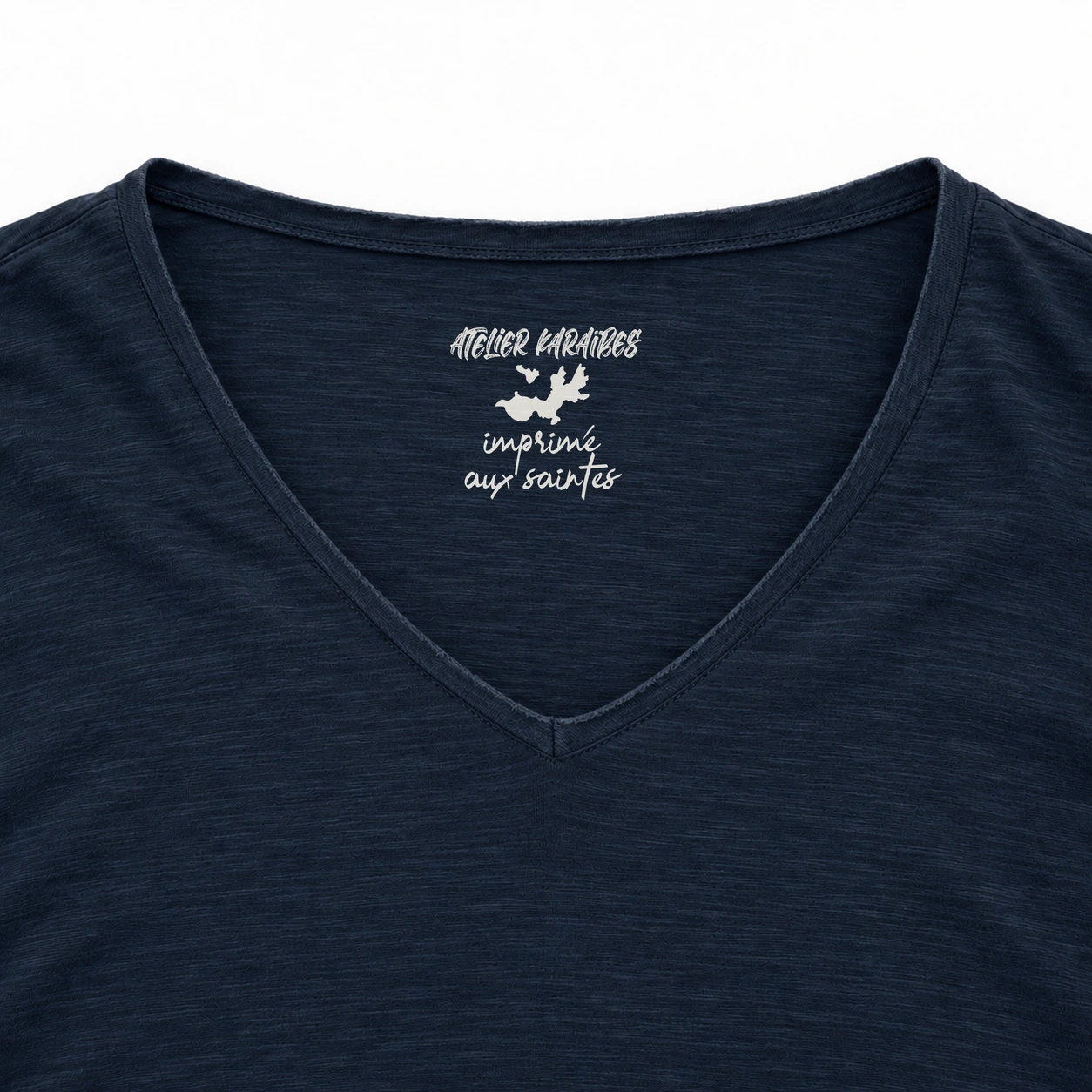 Étiquette intérieure Atelier Karaïbes « imprimé aux Saintes » en blanc sur le T-shirt col V Navy