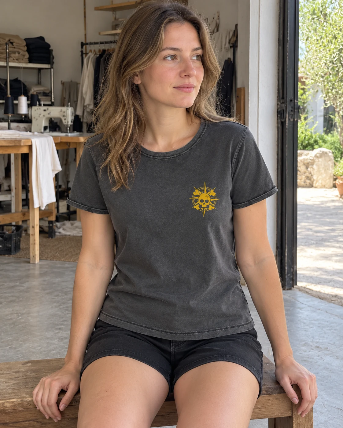 T-shirt vieilli femme gris anthracite délavé avec une boussole pirate 971 ornée d’un crâne imprimé en jaune moutarde, porté sur le ponton d’un petit voilier dans la baie des Sainte