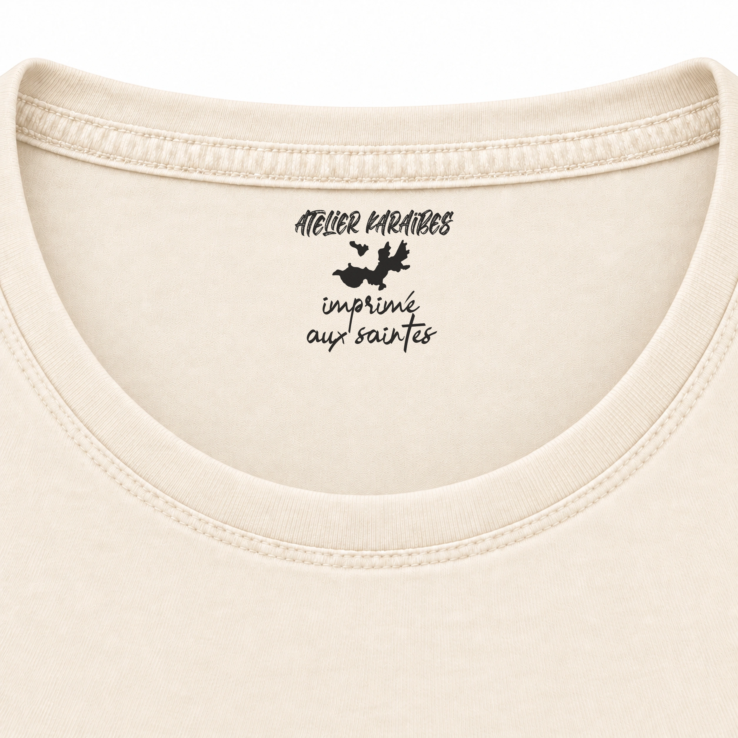 Étiquette intérieure Atelier Karaïbes « imprimé aux Saintes » en noir sur le T-shirt rouloté ivoire