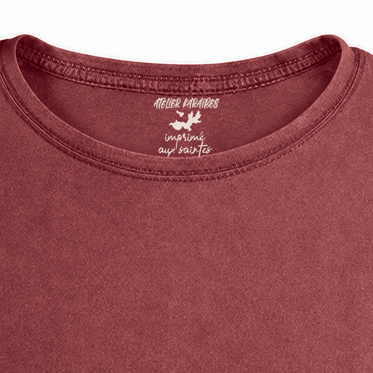 Gros plan de la signature intérieure Atelier Karaïbes imprimée en blanc sous le col du T-shirt vieilli homme rouge grenat délavé