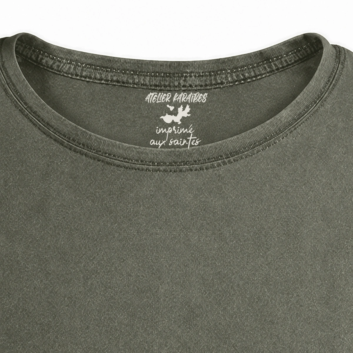 Gros plan de la signature intérieure Atelier Karaïbes imprimée en blanc sous le col du T-shirt vieilli homme vert militaire foncé délavé