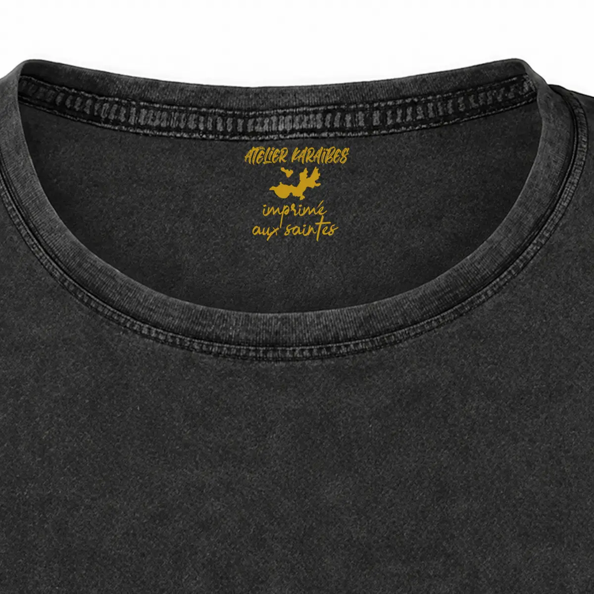 Gros plan de la signature intérieure Atelier Karaïbes imprimée en jaune moutarde sous le col du T-shirt vieilli femme gris anthracite délavé